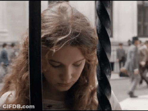 A Woman Behind Bars With Her Eyes Closed Looks Down GIF