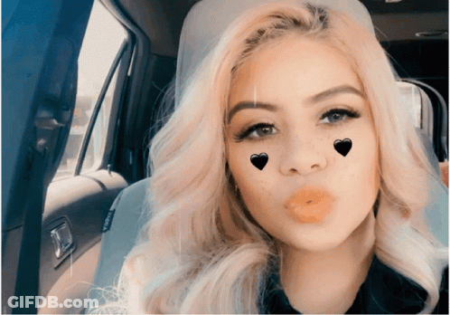A Woman Blowing A Kiss With Hearts On Her Face In A Car GIF