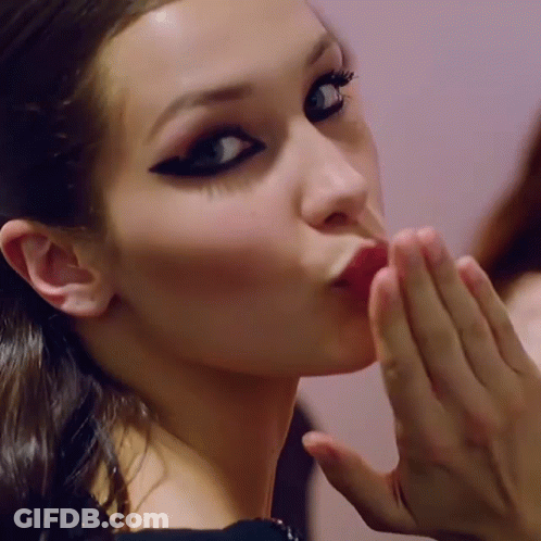 A Woman Blowing A Kiss With Her Hand GIF
