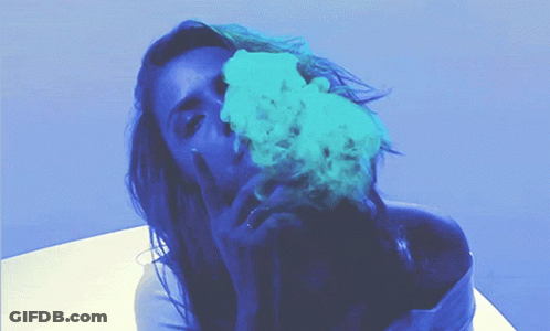 A Woman Blowing Blue Smoke From Her Mouth While Giving The Middle Finger GIF