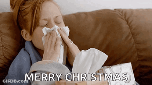 A Woman Blowing Her Nose While Sitting On A Couch With A Box Of Tissues In Front Of Her . GIF