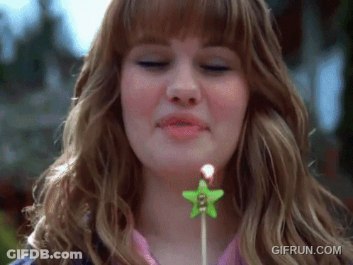 A Woman Blowing Out A Candle With A Star On It GIF
