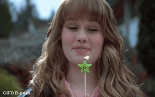 A Woman Blows Out A Green Star Candle GIF