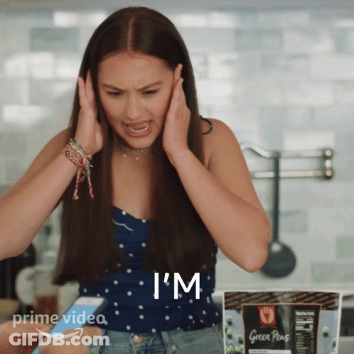 A Woman Covering Her Ears With Her Hands While Holding A Phone That Says I 'M GIF
