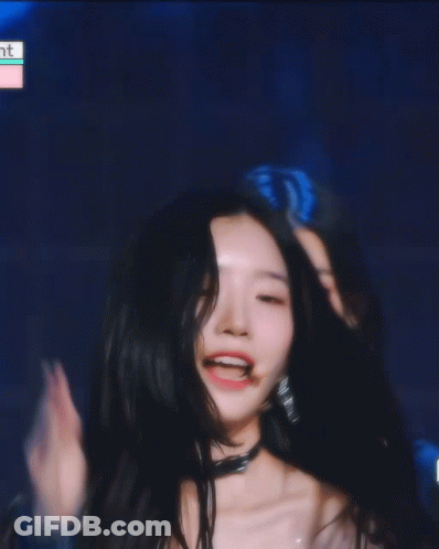 A Woman Covering Her Face With Her Hand And Smiling In Front Of A Blue Background GIF