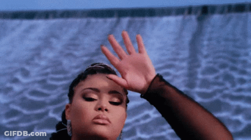 A Woman Covering Her Face With Her Hand In Front Of A Blue Background GIF