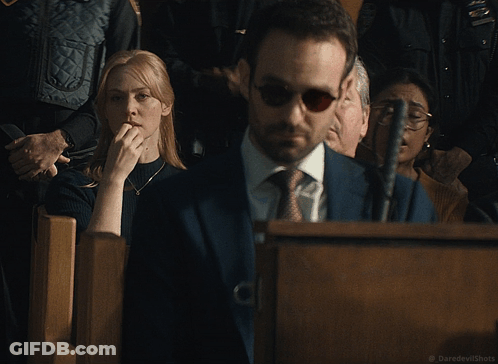 A Woman Covering Her Mouth While A Man In A Suit And Tie Looks On GIF