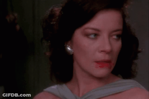 A Woman Covering Her Mouth With Her Hand While Looking At The Camera GIF