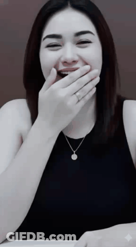 A Woman Covering Her Mouth With Her Hand While Wearing A Necklace And A Ring GIF