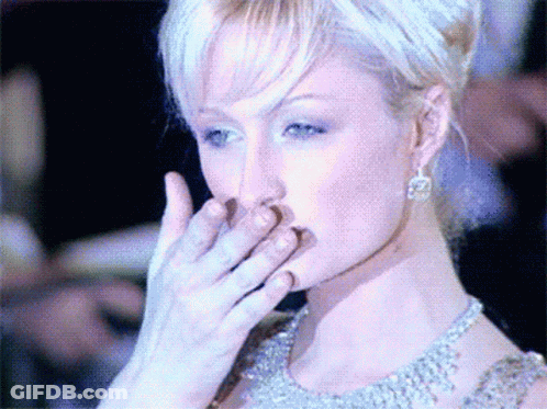 A Woman Covering Her Mouth With Her Hand While Wearing Earrings GIF