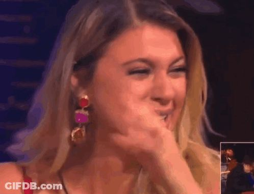 A Woman Covering Her Mouth With Her Hand While Wearing Earrings GIF