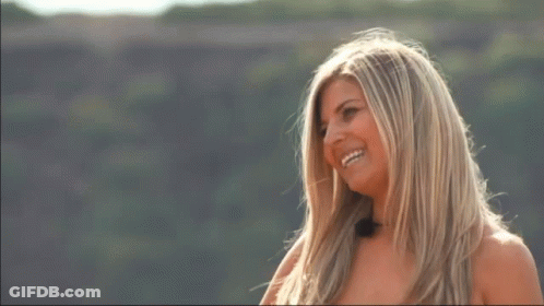 A Woman Covering Her Mouth With Her Hands While Standing On A Hill GIF