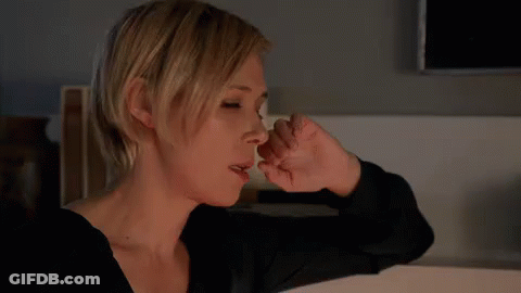 A Woman Covering Her Nose With Her Hand While Looking Down GIF