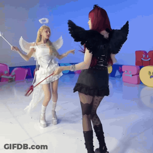 A Woman Dressed As An Angel And A Woman Dressed As A Devil Are Standing Next To Each Other GIF