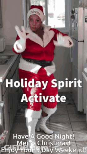 A Woman Dressed As Santa Claus Is Dancing In A Kitchen With The Words Holiday Spirit Activate Above Her GIF