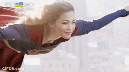 A Woman Dressed As Superman Is Flying Through The Air . GIF