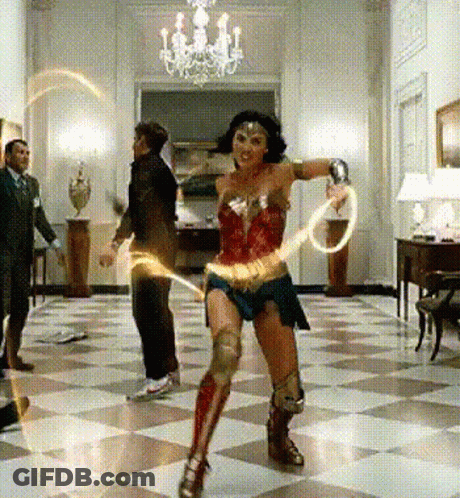 A Woman Dressed As Wonder Woman Is Dancing In A Room GIF