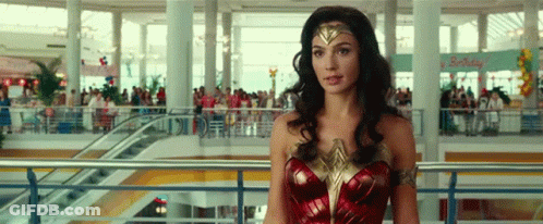 A Woman Dressed As Wonder Woman Is Standing In A Mall . GIF