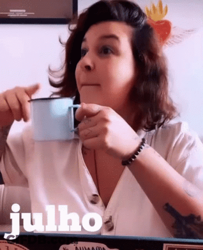 A Woman Drinking A Cup Of Coffee With The Word Julho Written In White GIF