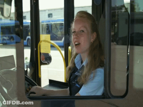 A Woman Driving A Bus With A Blue Shirt That Says ' Unitrans ' On The Front GIF