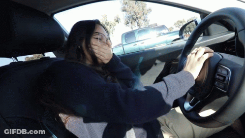 A Woman Driving A Car With Her Hand Over Her Mouth GIF