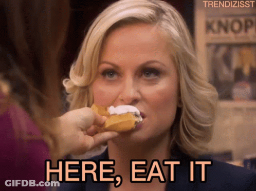 A Woman Eating A Donut With The Words Here Eat It Written Below Her GIF