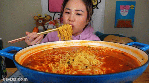 A Woman Eating Ramen With Chopsticks From A Pot GIF