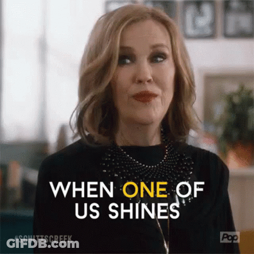 A Woman From Schitt 'S Creek Is Smiling And Saying `` When One Of Us Shines '' GIF