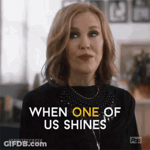 A Woman From Schitt 'S Creek Is Smiling And Saying `` When One Of Us Shines '' GIF