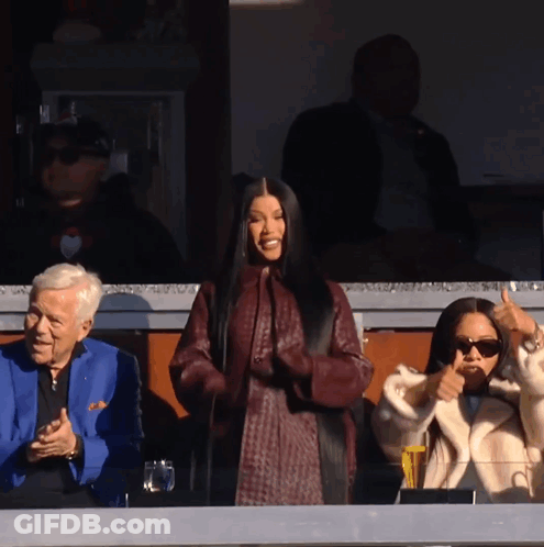A Woman Giving A Thumbs Up In Front Of A Man In A Blue Jacket GIF