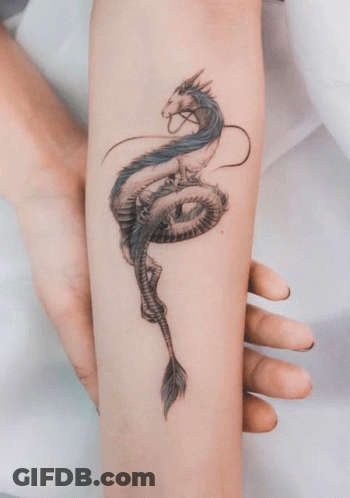 A Woman Has A Tattoo Of A Dragon On Her Forearm GIF