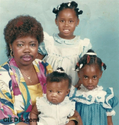 A Woman Holding A Baby And Two Little Girls Pose For A Photo GIF