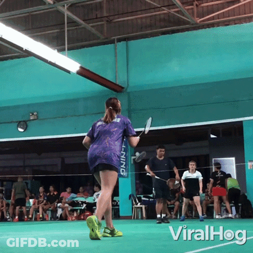 A Woman Holding A Badminton Racket In Front Of A Li Ning Banner GIF