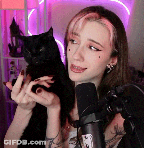A Woman Holding A Black Cat In Front Of A Microphone That Says Shure GIF