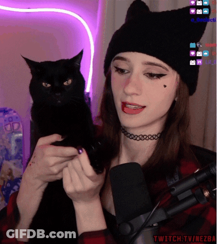 A Woman Holding A Black Cat In Front Of A Microphone With Twitch.tv/nezba Written On The Bottom Right GIF
