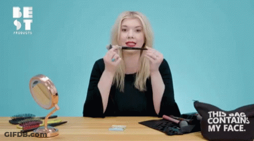 A Woman Holding A Blush Brush In Front Of A Bag That Says " This Bag Contains My Face " GIF