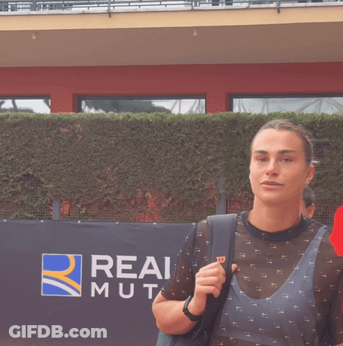A Woman Holding A Bottle Of Water And Wearing A Shirt With The Letter W On It GIF