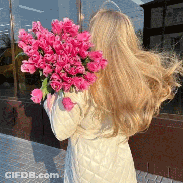 A Woman Holding A Bouquet Of Pink Flowers GIF