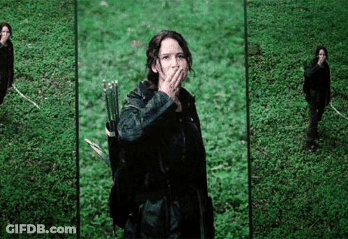 A Woman Holding A Bow And Arrow Covering Her Mouth GIF