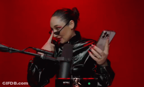 A Woman Holding A Cell Phone In Front Of A Microphone With The Word Obstacle On The Bottom GIF