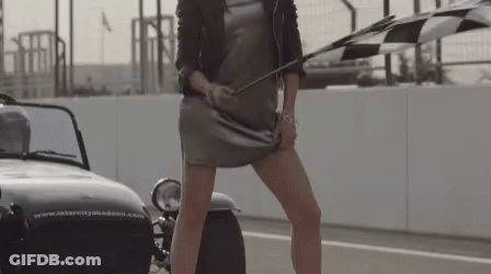 A Woman Holding A Checkered Flag In Front Of A Car That Says Intercity Academy GIF