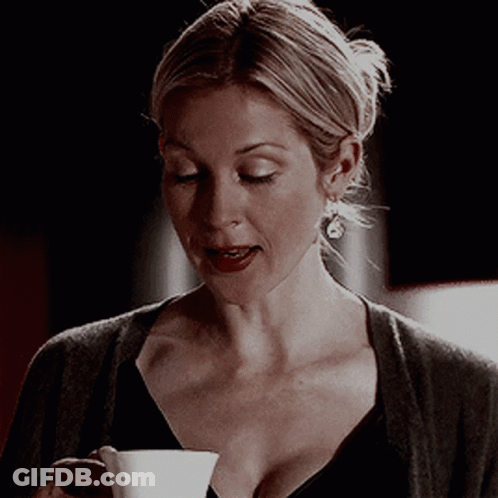 A Woman Holding A Cup Of Coffee In Her Hand GIF