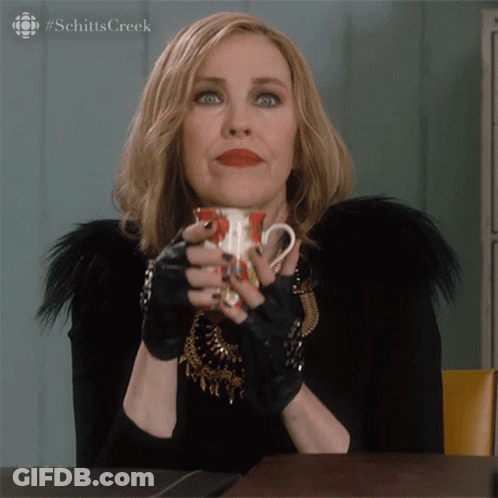A Woman Holding A Cup Of Coffee With The Hashtag Schitts Creek GIF