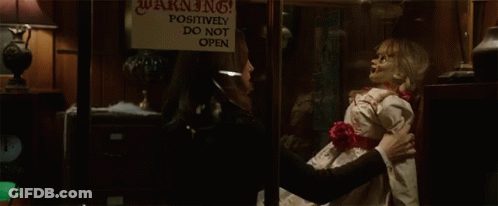 A Woman Holding A Doll In Front Of A Warning Sign GIF