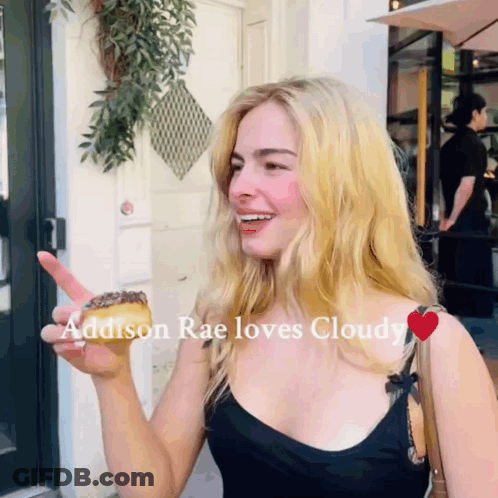 A Woman Holding A Donut With The Words Addison Rae Loves Cloudy GIF