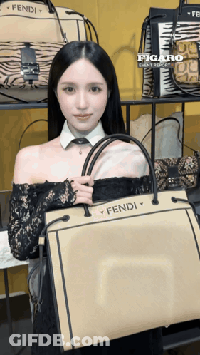 A Woman Holding A Fendi Bag In Front Of A Display Of Bags GIF
