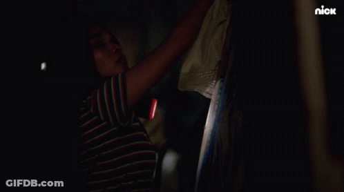 A Woman Holding A Flashlight In A Dark Room With A Nick Logo On The Bottom GIF