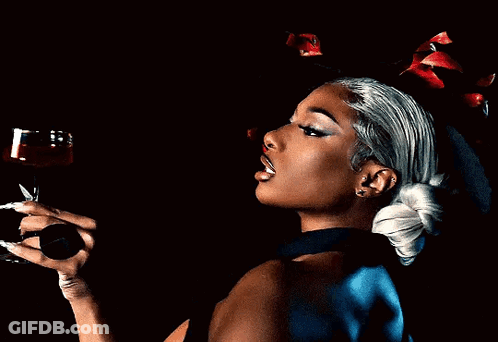A Woman Holding A Glass Of Red Wine In Her Hand GIF