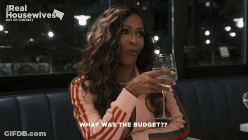 A Woman Holding A Glass Of Water With The Words What Was The Budget Below Her GIF