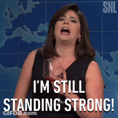 A Woman Holding A Glass Of Wine With The Words I 'M Still Standing Strong GIF